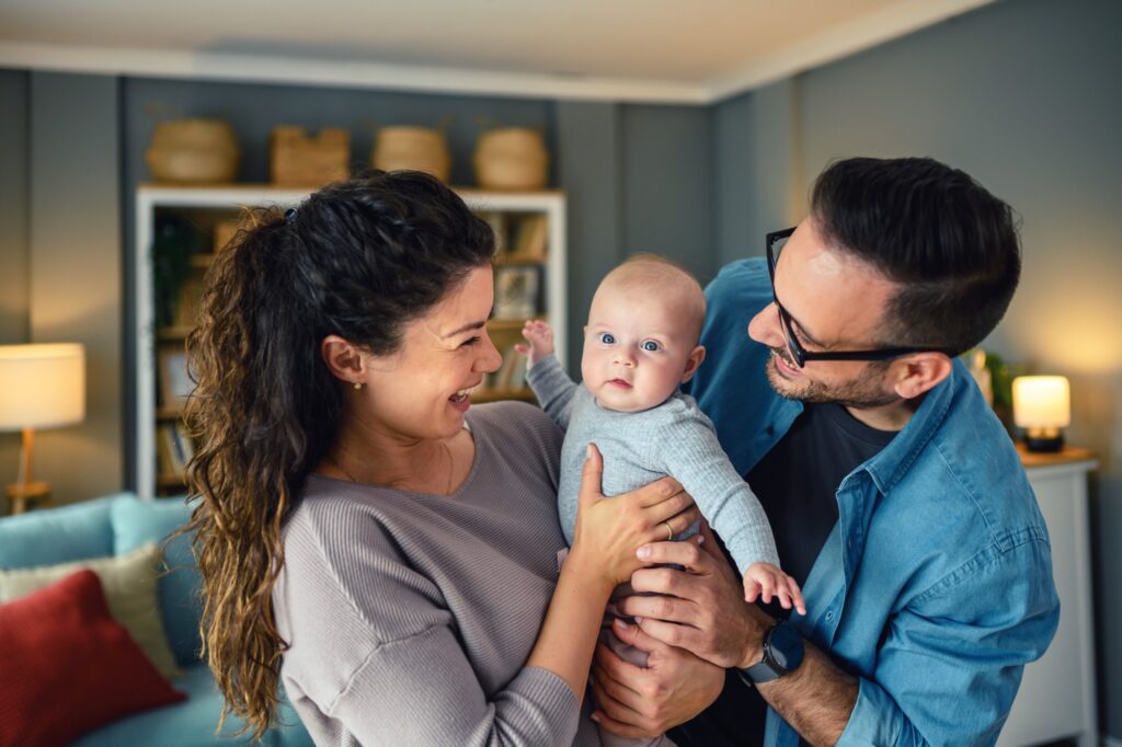 Happy parents holding their baby at home.
