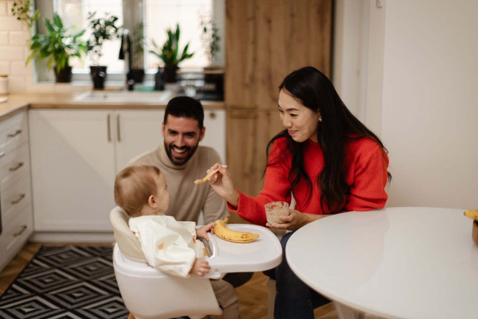 Family feeding baby in kitchen together.