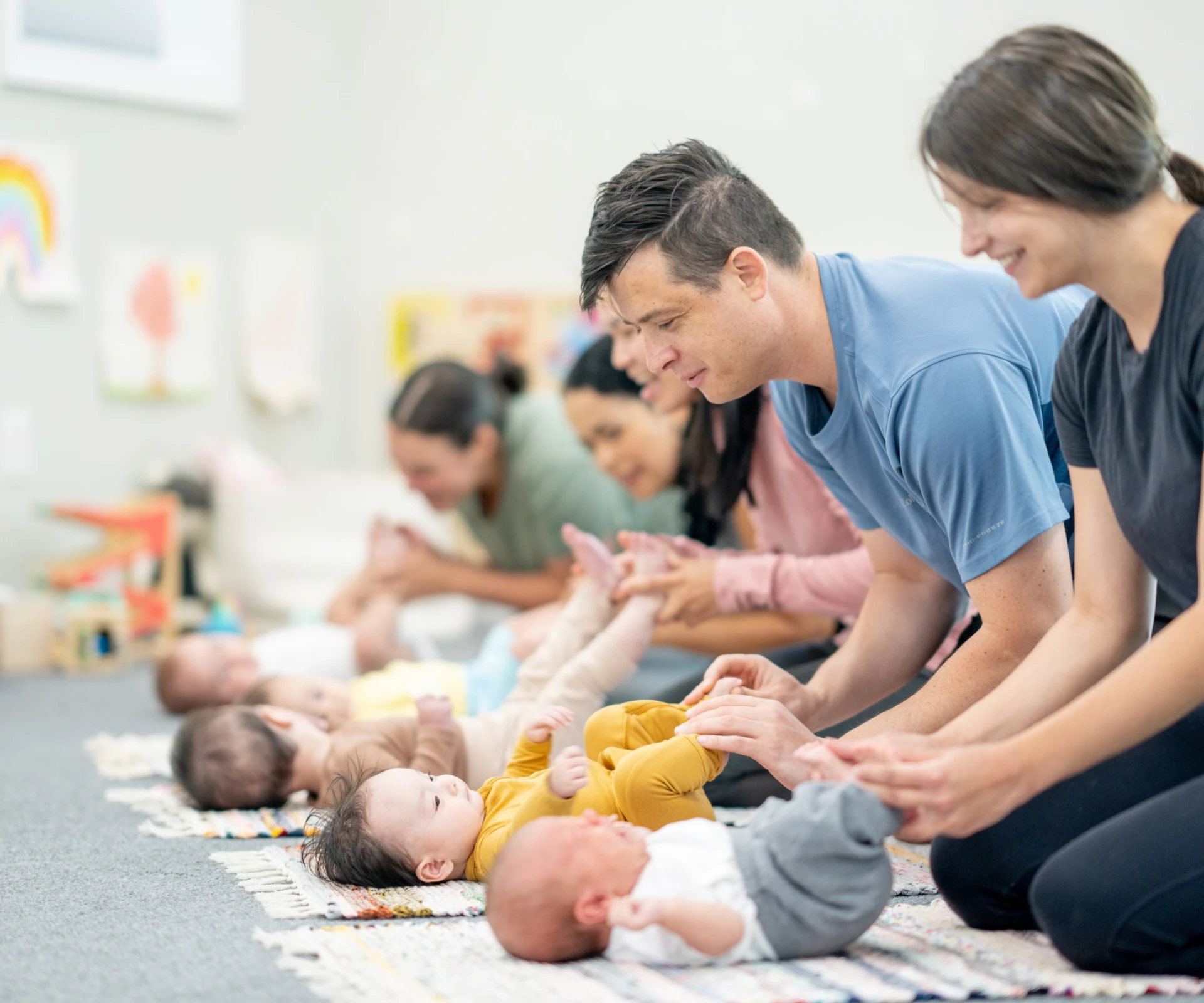Parents playing with babies on mats.