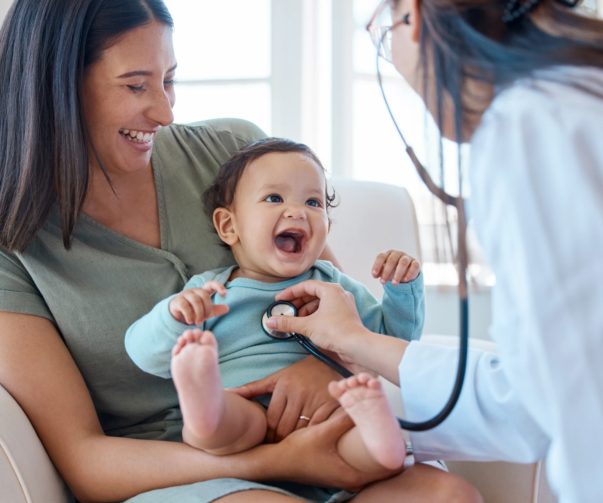 Smiling baby with doctor and mother.