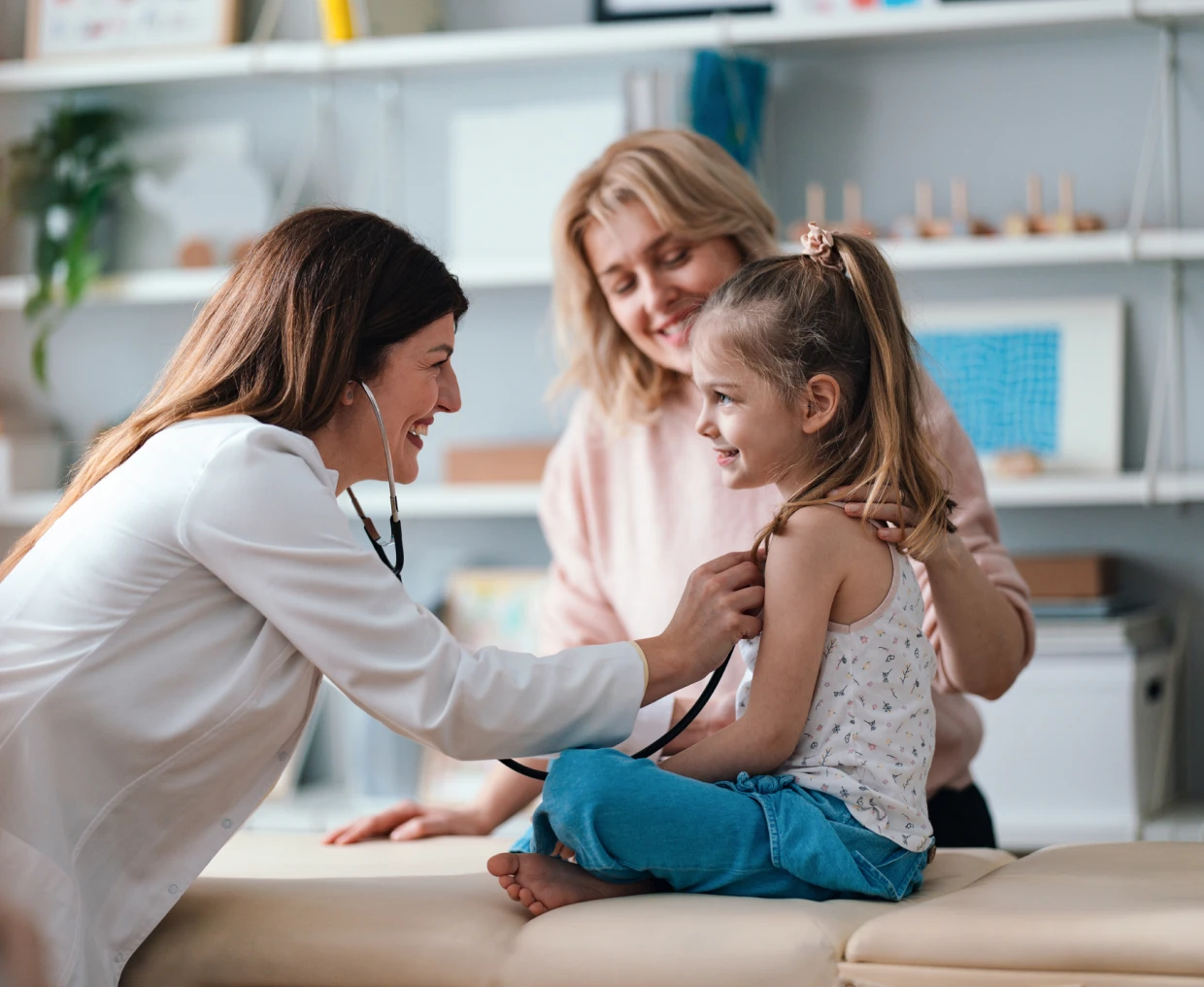 Doctor examining smiling child with stethoscope.