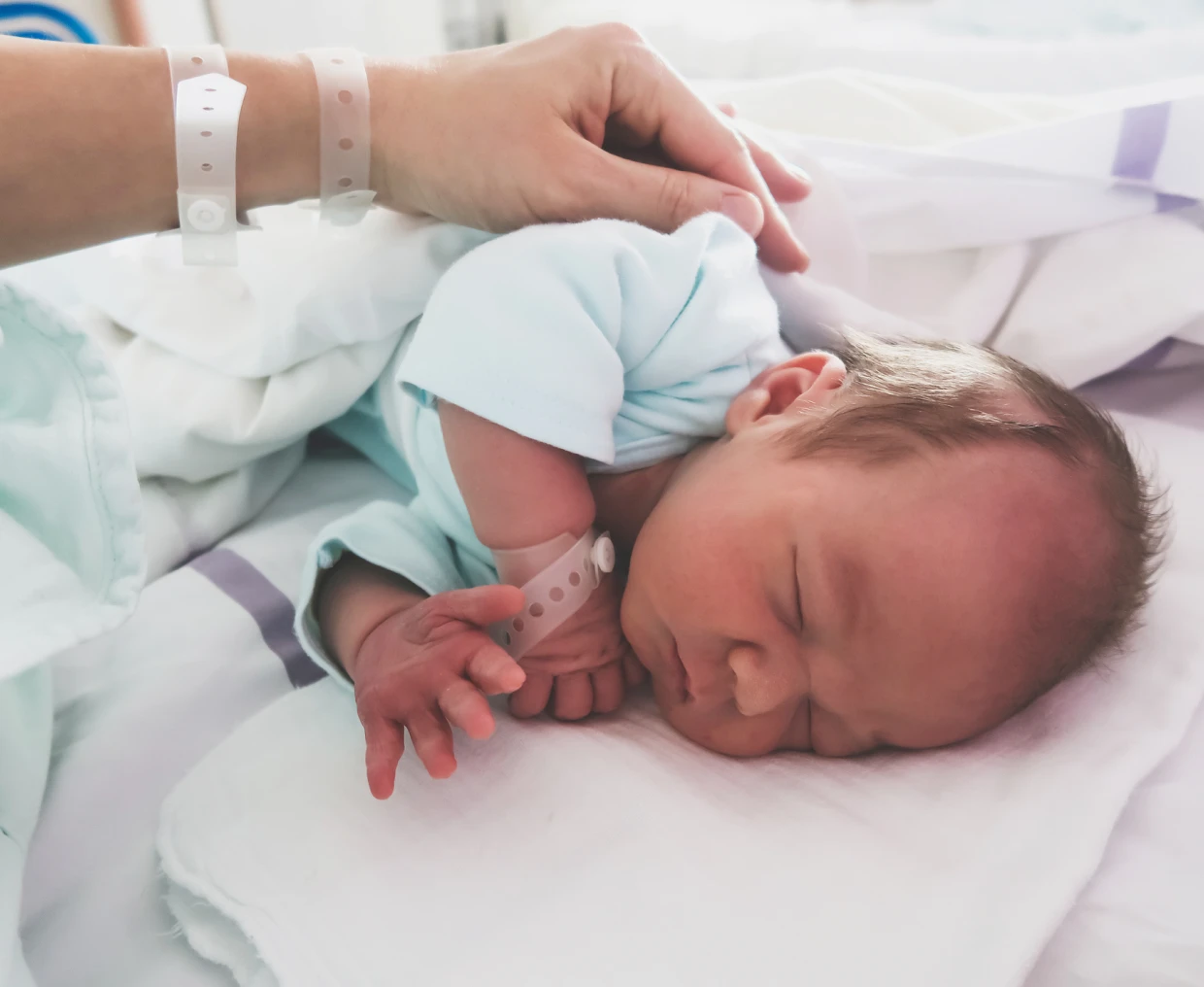 Newborn baby sleeping with hospital bracelet.