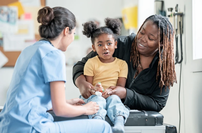 Child with parent and nurse in clinic.